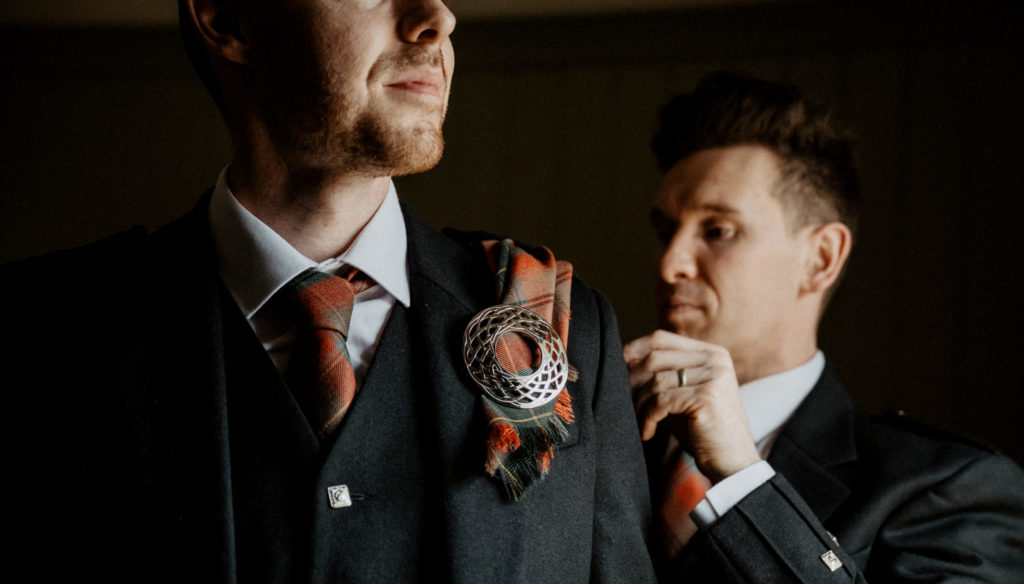 Groomsmen on their wedidng day adjusting a Tartan Fly Plaid and Brooch